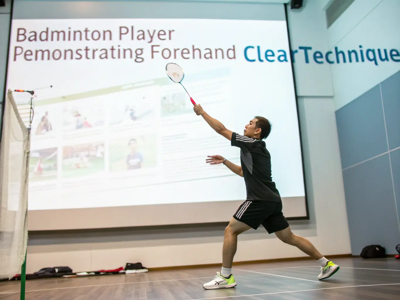 A dynamic shot of a badminton coach instructing a group of young players, emphasizing skill development and teamwork in a youth program.